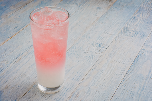 Kamoti Summer Fizz cocktail in a tall glass with a pink gradient over ice