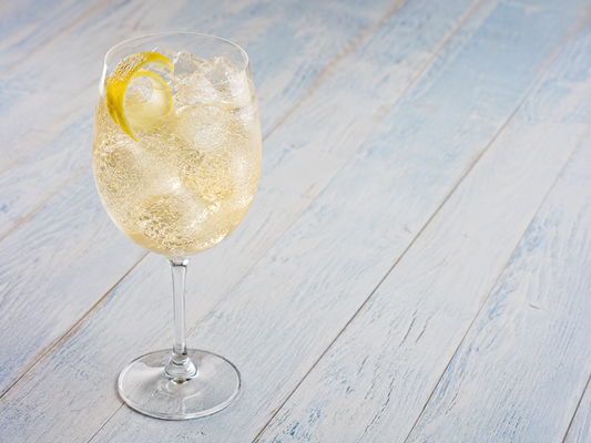 White Tea Spritz in a wine glass with ice and a lemon twist