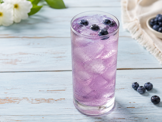 White Tea Blueberry Breeze in a tall glass with ice and fresh blueberries