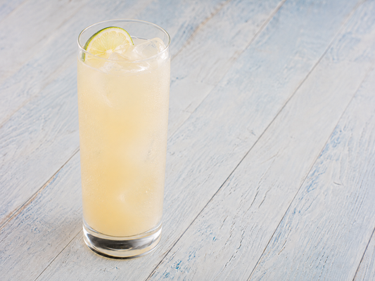 Green Tea Coconut Cooler in a tall glass with ice and a lime wheel
