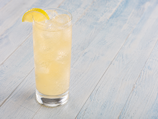 White Tea Lemonade in a tall glass with ice and a lemon wedge